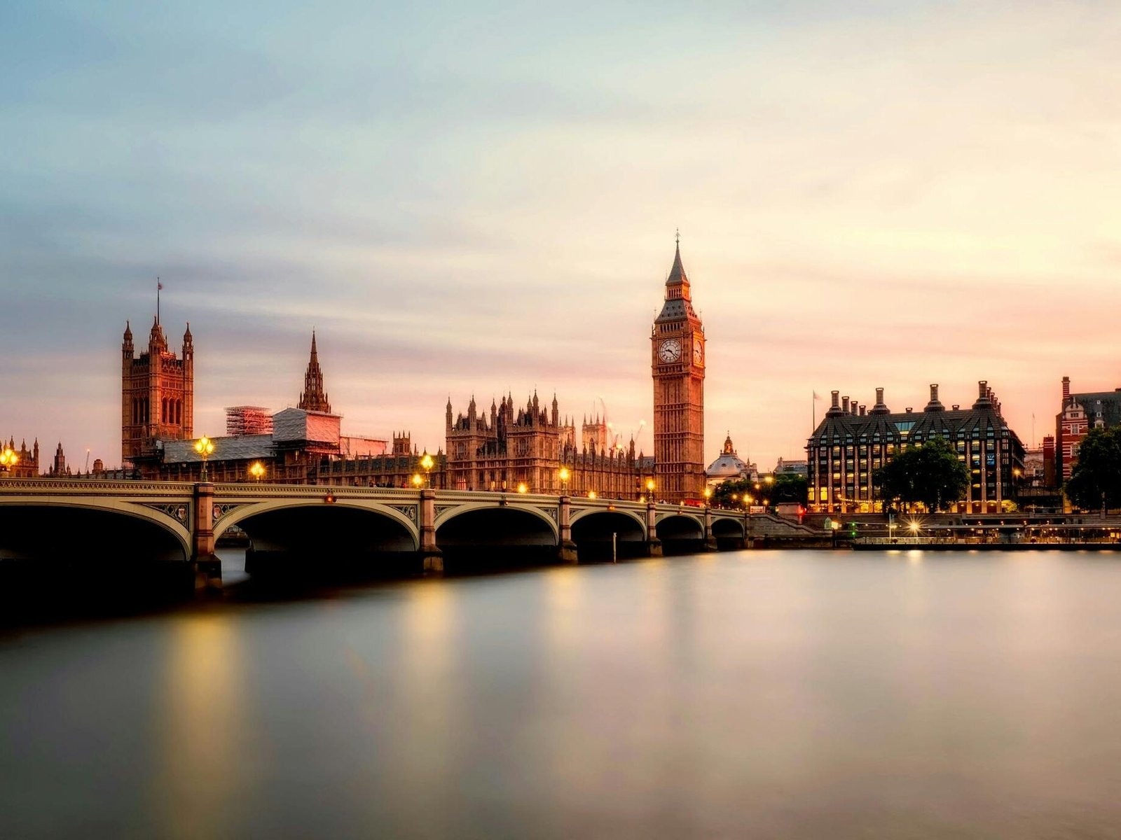 Scenic view of Big Ben and Westminster Bridge over the Thames River at sunset in London, UK.